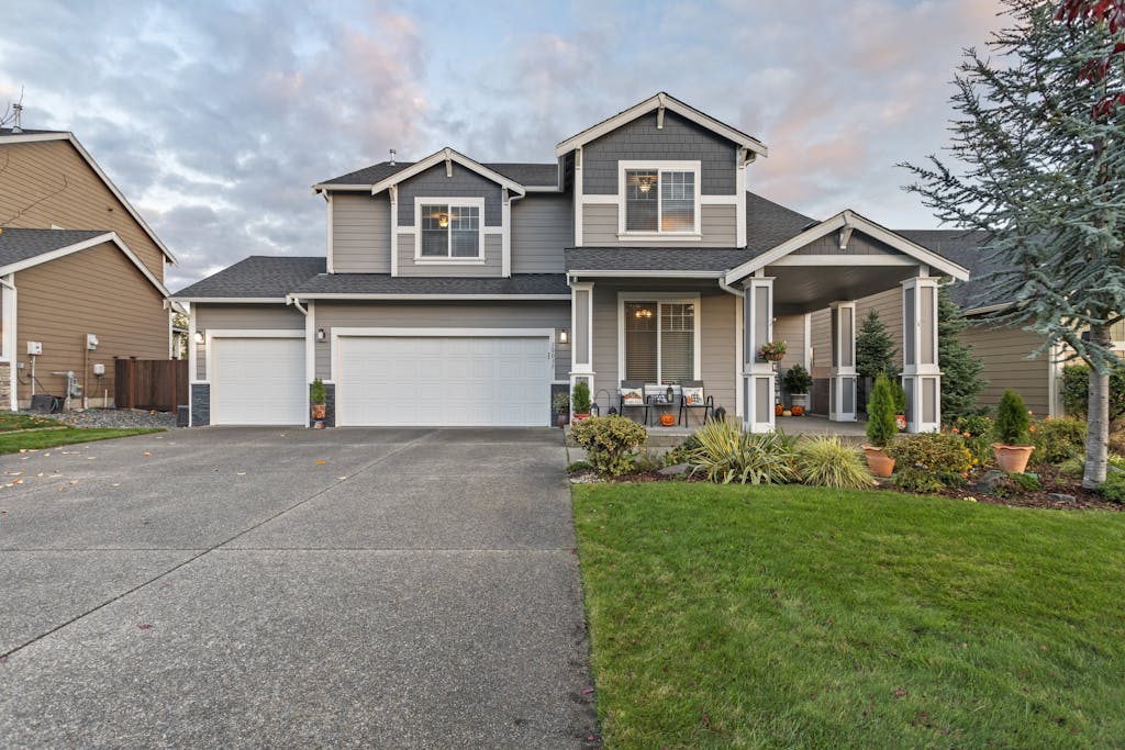 Charming two-story house with manicured lawn and garage, set in Vancouver, WA, under dusk sky.